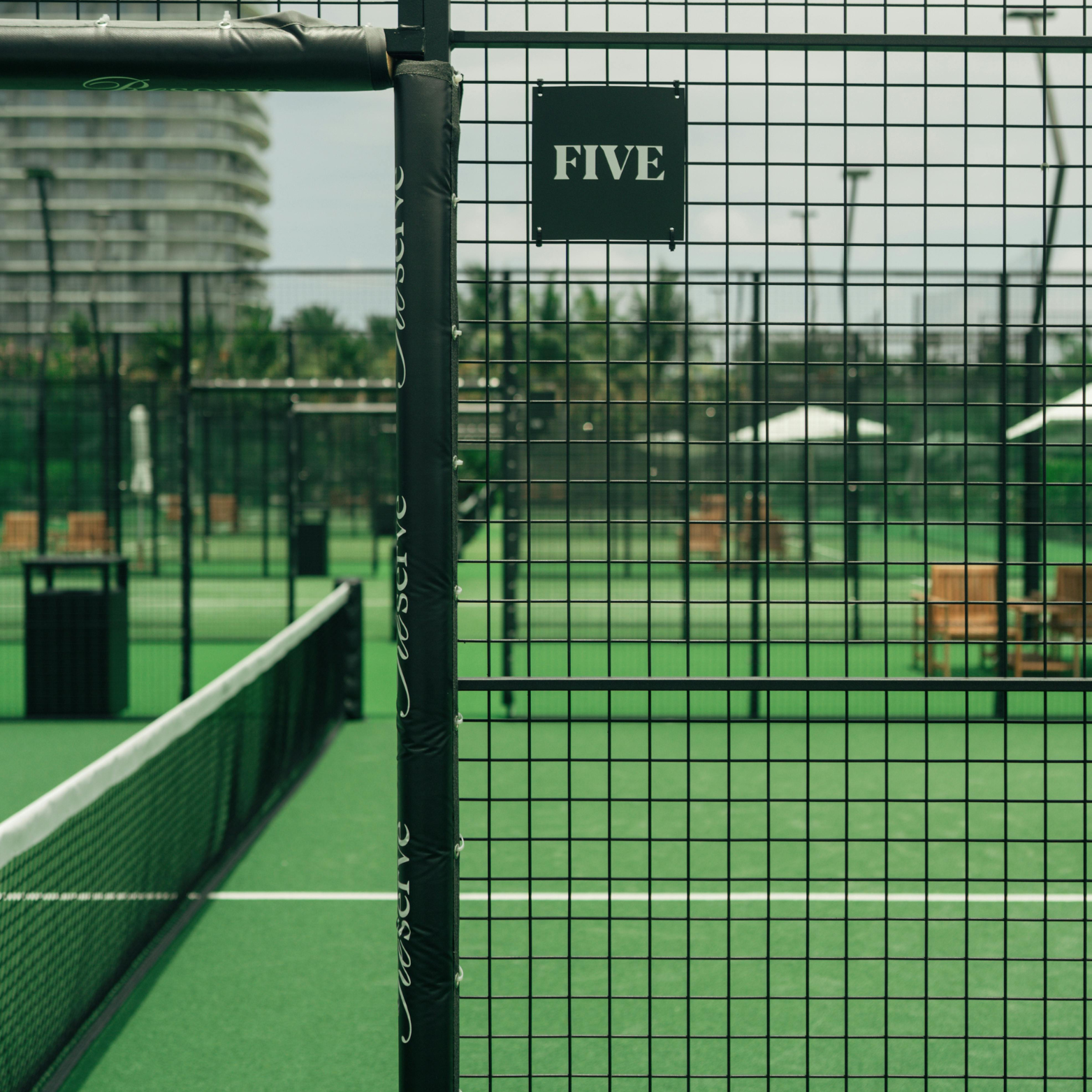 Tennis court with a net and 'FIVE' sign on a fence
